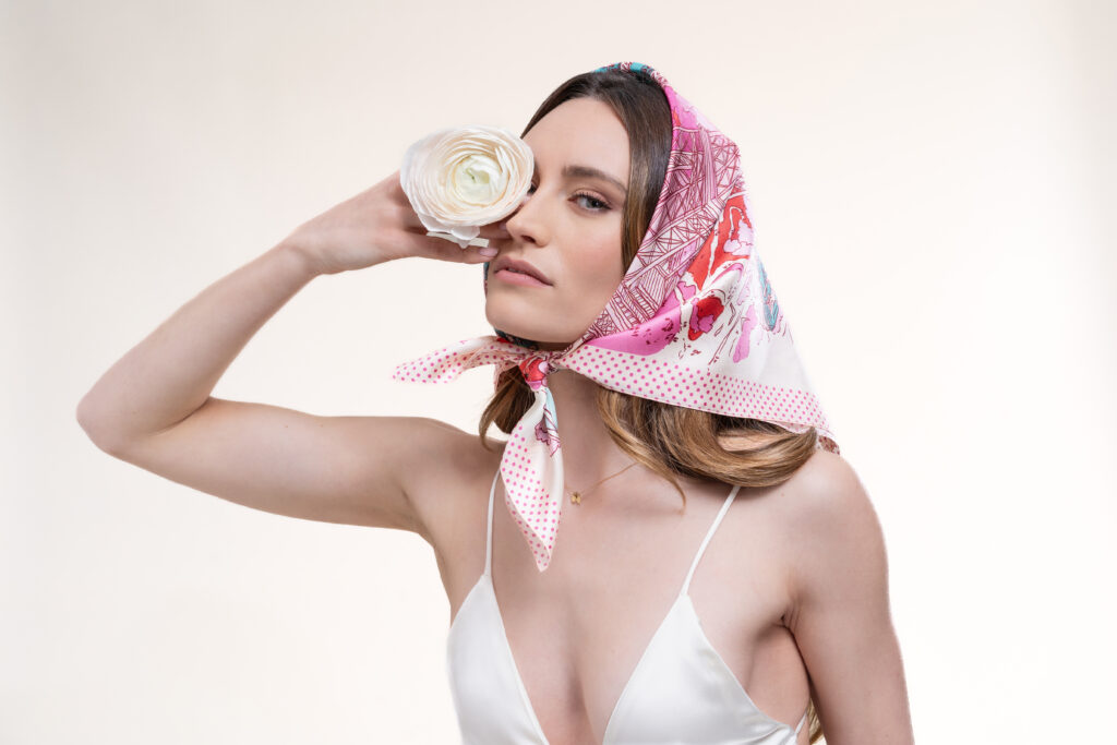 Écharpe élégante aux motifs japonais présentée par un modèle dans un décor floral raffiné. Le tissu bleu nuit dévoile des grues, carpes koï et fleurs symboliques