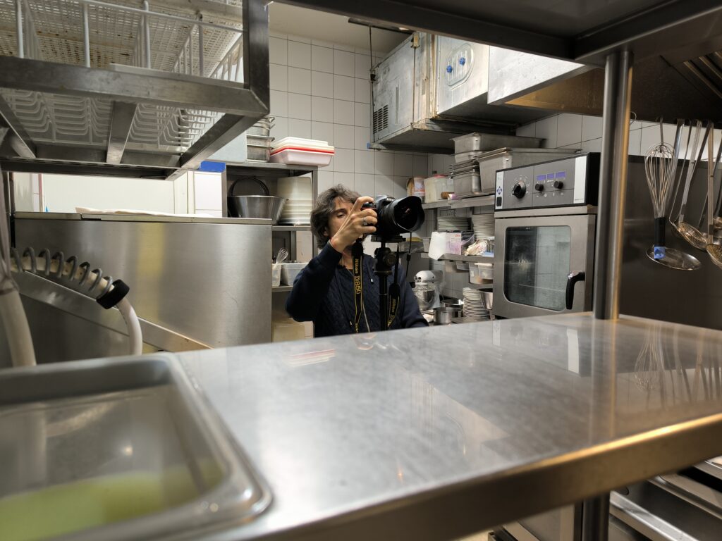 Photographe prenant une photo dans une cuisine professionnelle en inox.