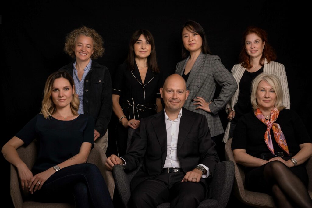 Portrait corporate en studio d'une équipe dirigeante de sept personnes, fond noir, tenues sombres. Studio Alterego